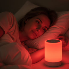 Woman relaxing in bed with a portable 670nm red light lamp creating a warm, calming glow
